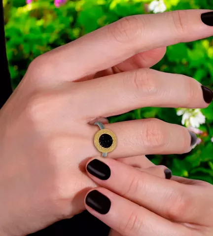 anillo de acero y oro con cristales negros toma mano femenina