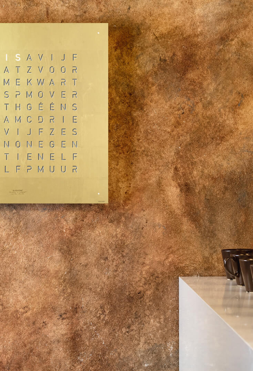 Qlocktwo Stainless Steel Gold reloj de pared letras colgado parcial