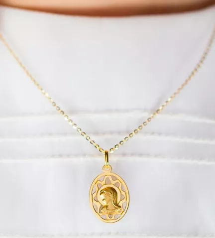 medalla religiosa de oro virgen niña ovalada y calada sobre traje de comunion